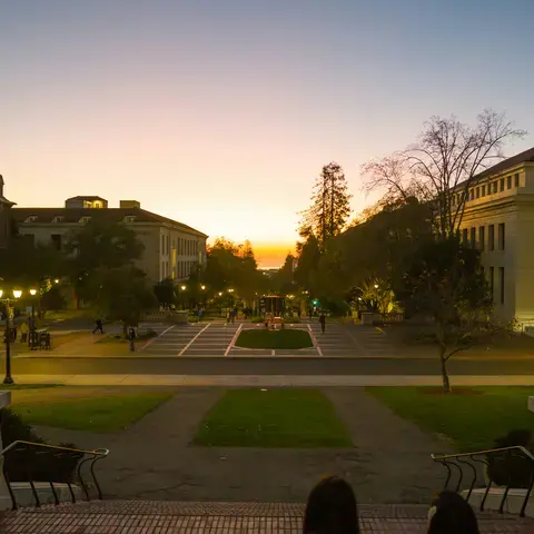 University campus at sunset, with soft golden light illuminating the courtyard and surrounding historic buildings