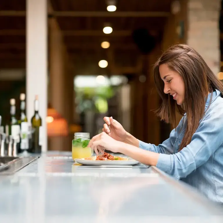 Girl sitting at restaurant bar and enjoying meal