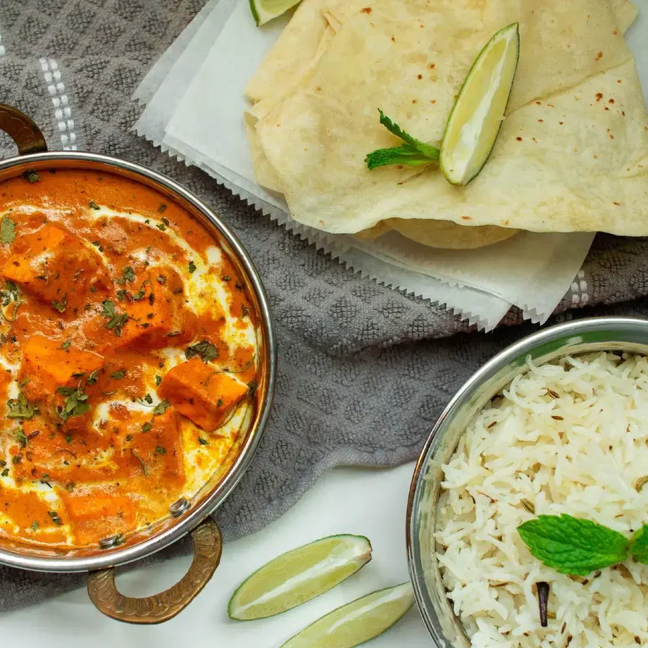 an overhead shot of a bowl of curry and rice and some poppadoms