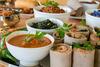 A colorful Ethiopian feast with spicy stew, leafy greens, and injera rolls, garnished with parsley on a serving tray