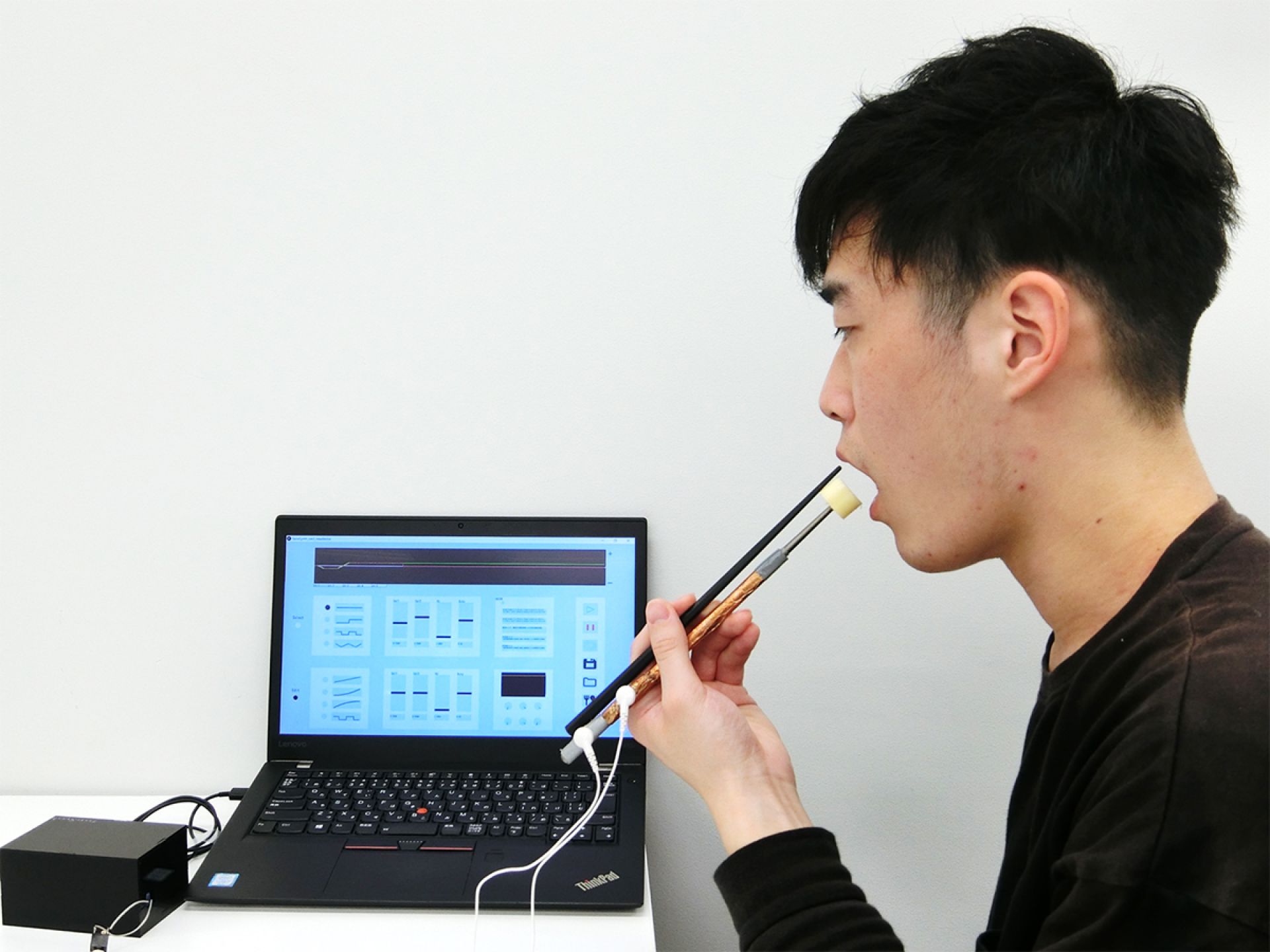 a man testing electric chopsticks with laptop