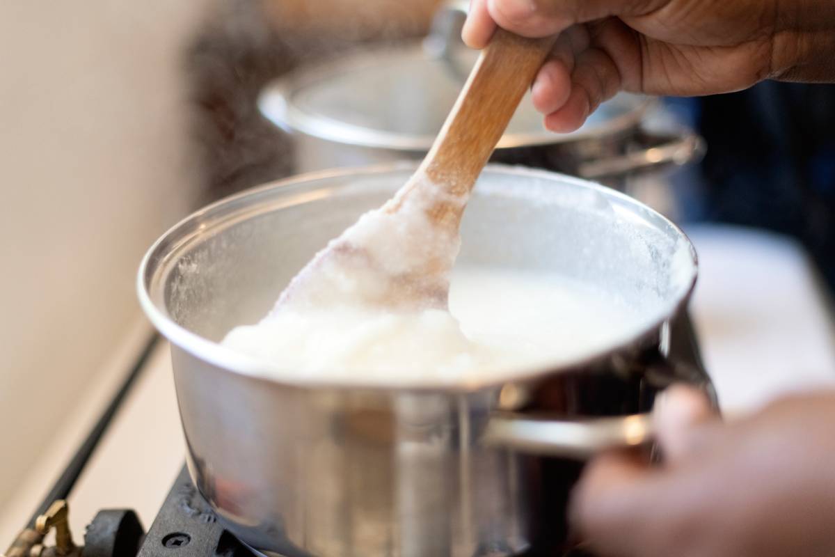 Woman preparing porridge cooking cornmeal with water